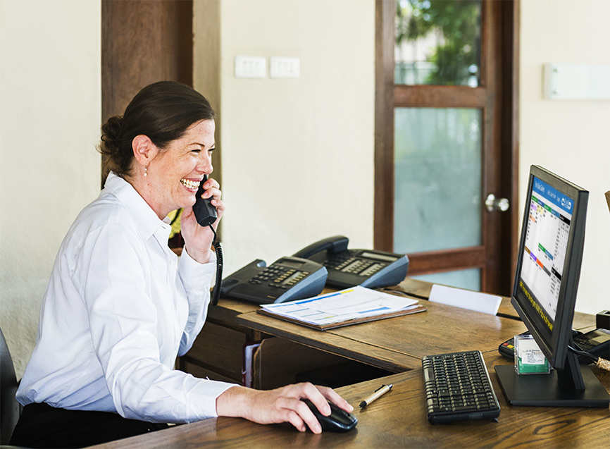Receptionist using Sales Rotor on her computer while assisting a guest by phone.